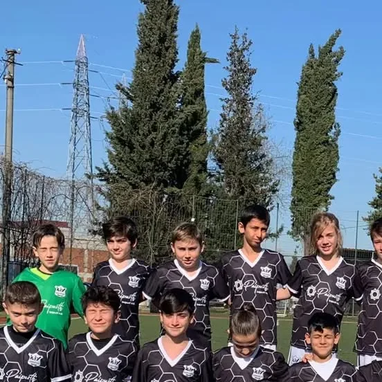 Geometrik desenli siyah-beyaz formalarla açık sahada takım fotoğrafı