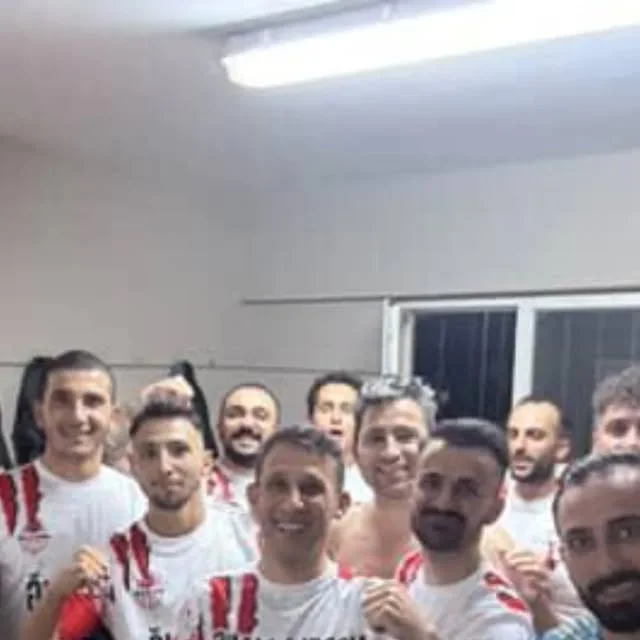 Kırmızı-beyaz formalarını giyen takımın kapalı alandaki fotoğrafı